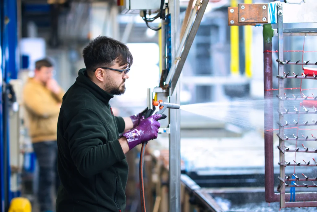 Oberflächenbeschichter bei der Arbeit in der Galvanik Mitarbeiter in der Galvanotechnik überwacht den Beschichtungsprozess von Metallteilen