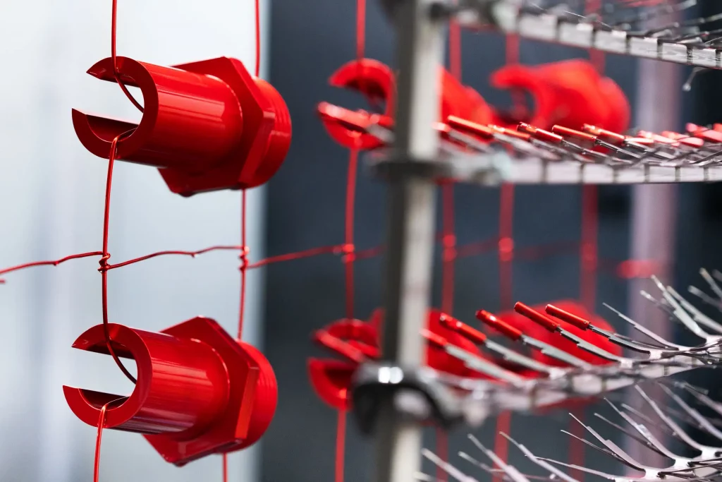 Eloxalprozess: Bildung einer Aluminiumoxidschicht auf Bauteilen Rot eloxierte Aluminiumbauteile im Gestell während der anodischen Oxidation