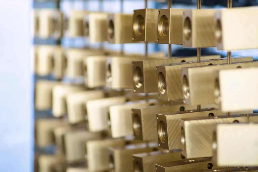 Chromatieren technischer Aluminiumbauteile vor Weiterverarbeitung Aluminiumblöcke mit goldfarbener Chromatschicht während des Gestellprozesses in der Oberflächentechnik