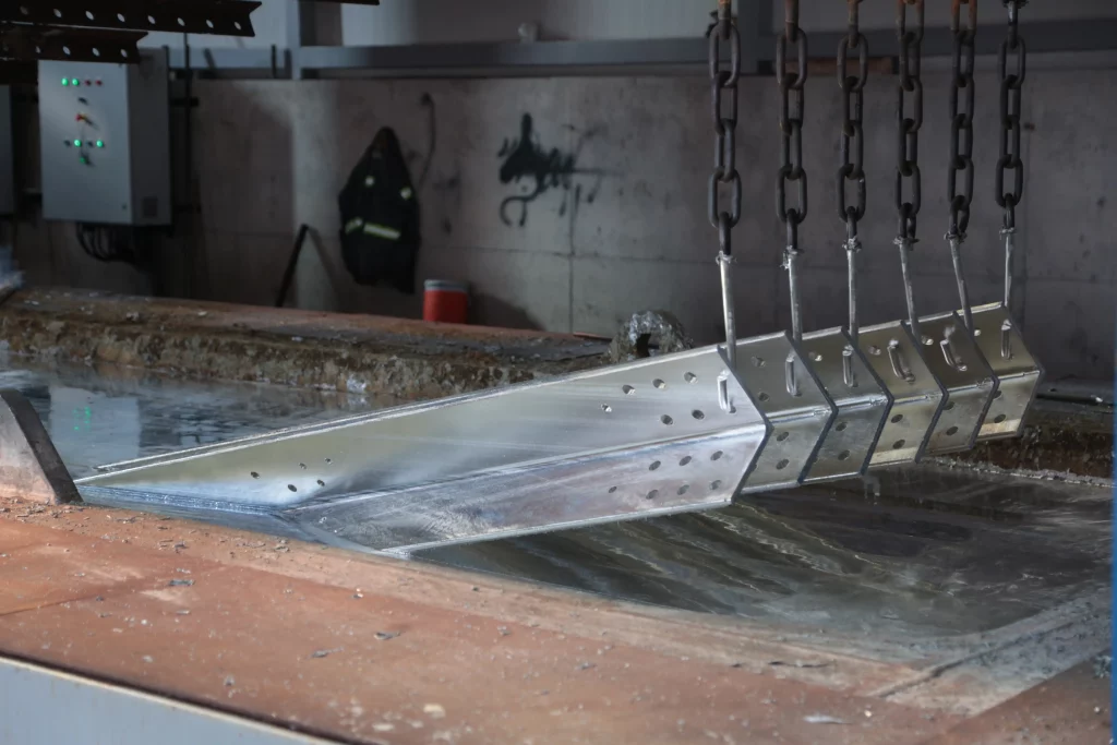 Chemisches Chromatieren von Aluminiumkomponenten im Tauchbad Aluminiumkomponenten an Transportketten im Tauchbad während der chemischen Konversionsbeschichtung im Rahmen der Chromatierung