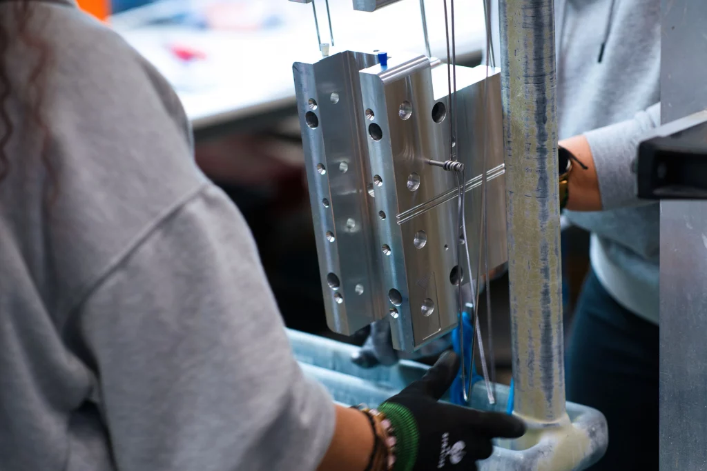 Vorbereitung von Aluminiumbauteilen für den Beizprozess Mitarbeiter befestigen ein Aluminiumbauteil auf einem Warenträger für die Beize und das anschließende Eloxieren