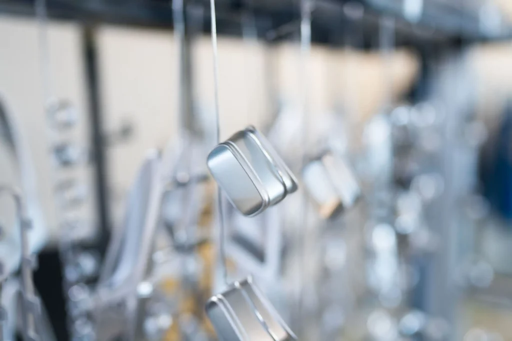Geeignete Bauteile zum Elektropolieren Kleine Metallbauteile hängen an einer Aufhängung für die Oberflächenbehandlung